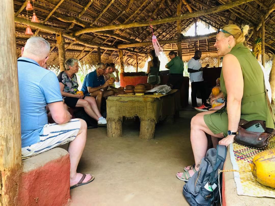 Guests sitting with village hosts under a thatched hut near Habarana